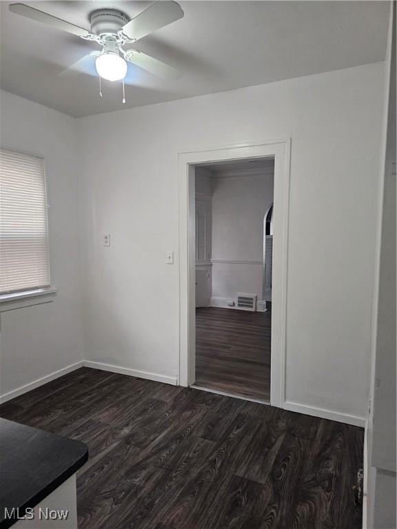 unfurnished room with baseboards, dark wood-style flooring, and ceiling fan