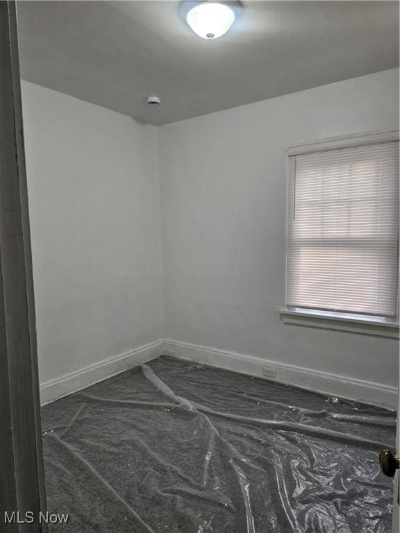 unfurnished room with baseboards
