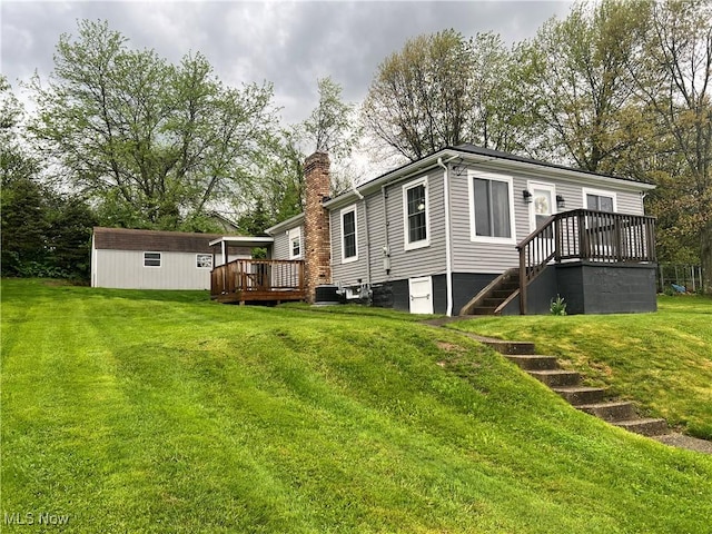 rear view of house with a chimney, a deck, stairway, an outdoor structure, and a yard