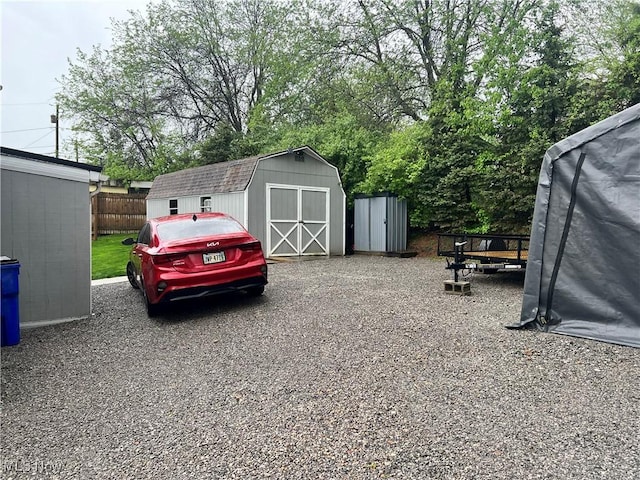 view of parking with fence and a shed