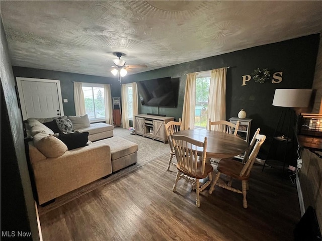 living area with a ceiling fan, plenty of natural light, and wood finished floors