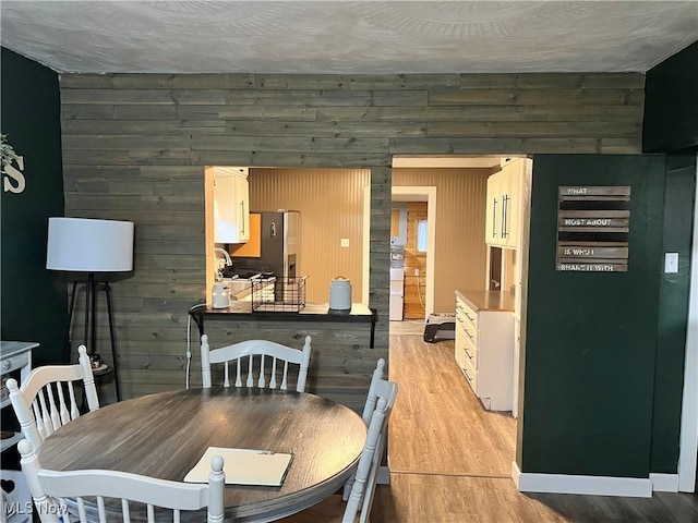 dining area with wooden walls and light wood-type flooring