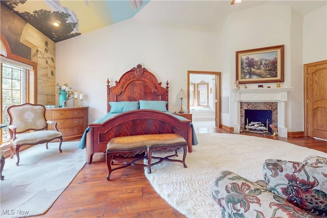 bedroom featuring high vaulted ceiling, wood finished floors, and a fireplace