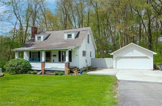 view of front of house featuring an outdoor structure, a front lawn, a detached garage, a chimney, and covered porch
