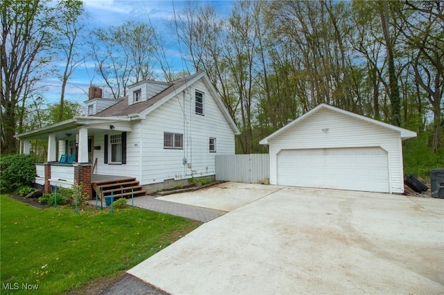 view of home's exterior featuring an outdoor structure, a garage, a lawn, a chimney, and a porch