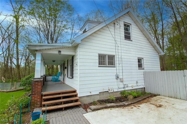 view of home's exterior with fence and a porch