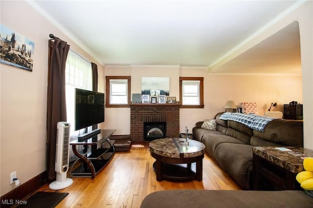 living room featuring a brick fireplace, ornamental molding, and hardwood / wood-style flooring