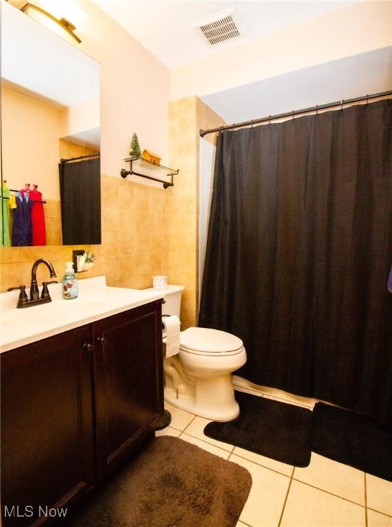 full bathroom featuring visible vents, vanity, toilet, tile walls, and tile patterned floors