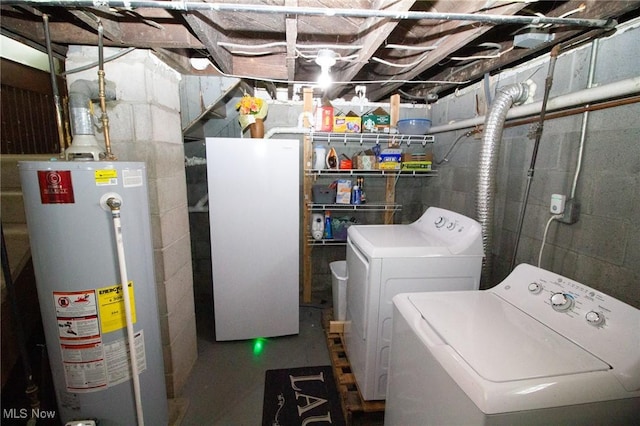 washroom with water heater, concrete block wall, laundry area, and washing machine and clothes dryer