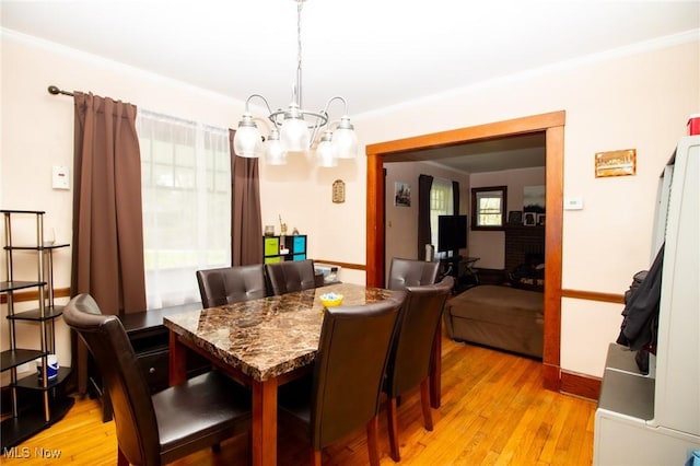 dining area with light wood-type flooring, baseboards, and a chandelier