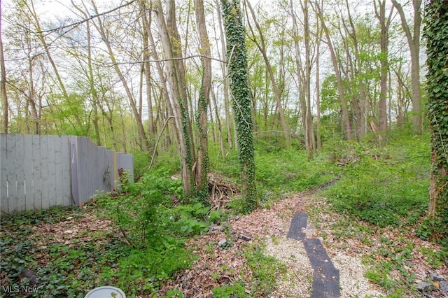 view of yard featuring fence and a wooded view