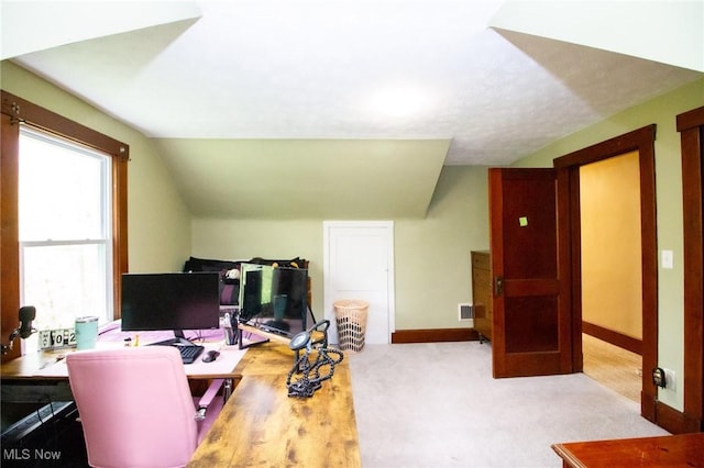 carpeted home office featuring baseboards, vaulted ceiling, and visible vents