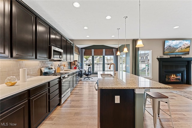 kitchen with a healthy amount of sunlight, backsplash, a sink, a breakfast bar, and stainless steel appliances
