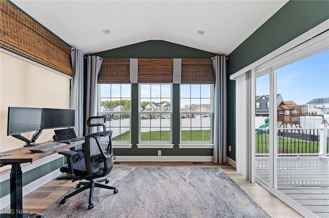 home office with baseboards, wood finished floors, lofted ceiling, visible vents, and a residential view