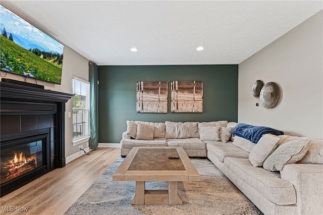 living area with baseboards, recessed lighting, a tile fireplace, and wood finished floors