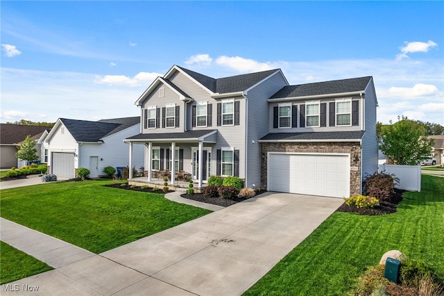traditional-style home with covered porch, a front yard, a garage, concrete driveway, and stone siding