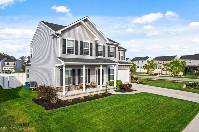 traditional-style house featuring a front yard, a gate, concrete driveway, cooling unit, and covered porch