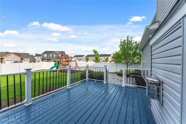 wooden terrace with a residential view, a lawn, a playground, and a fenced backyard
