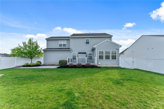 back of property with a fenced backyard, a yard, and a gate