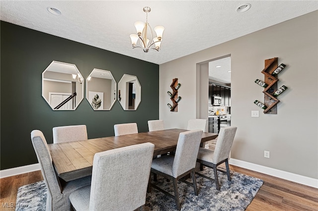 dining space with wood finished floors, baseboards, recessed lighting, a textured ceiling, and a chandelier