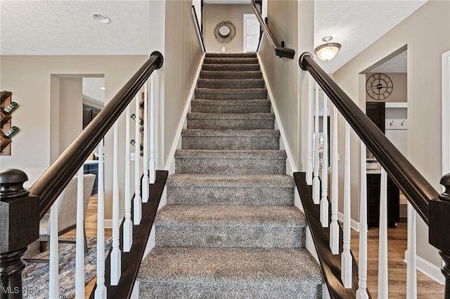 stairs with baseboards, a textured ceiling, and wood finished floors