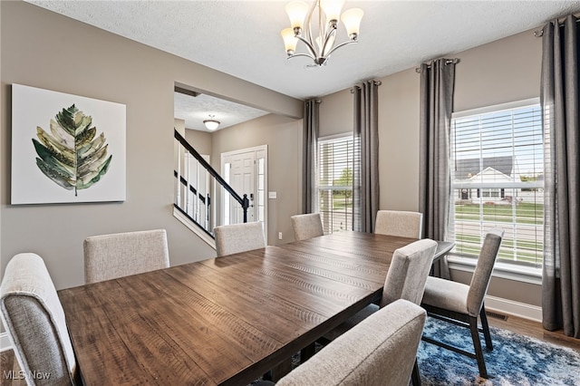 dining area with stairs, baseboards, a chandelier, and wood finished floors