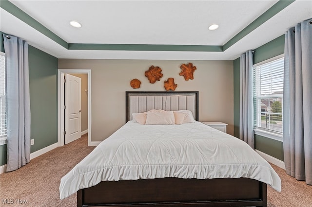carpeted bedroom featuring baseboards, recessed lighting, and a raised ceiling