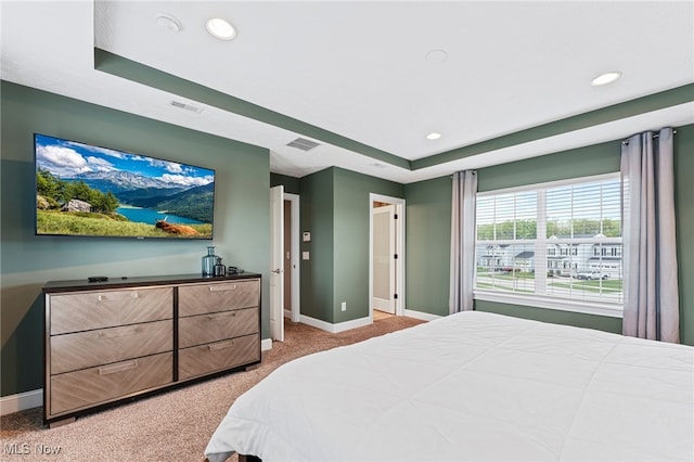 bedroom featuring baseboards, a raised ceiling, visible vents, and light carpet