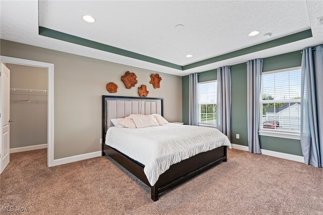 bedroom with carpet floors, baseboards, and a tray ceiling