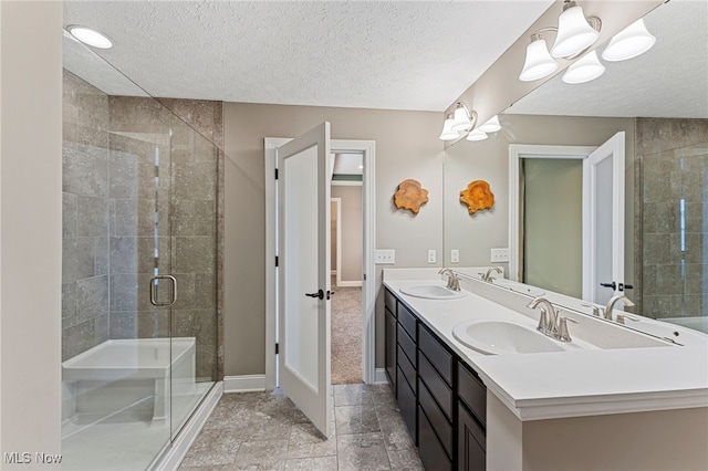 bathroom with a sink, baseboards, a stall shower, and a textured ceiling