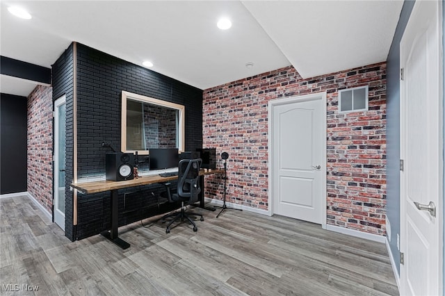home office with baseboards, brick wall, and wood finished floors