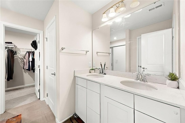 full bathroom featuring visible vents, a sink, a stall shower, and double vanity