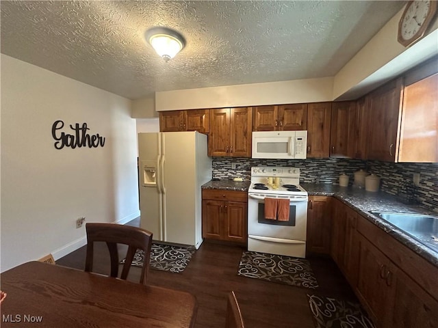 kitchen with dark countertops, white appliances, a textured ceiling, backsplash, and dark wood-style floors