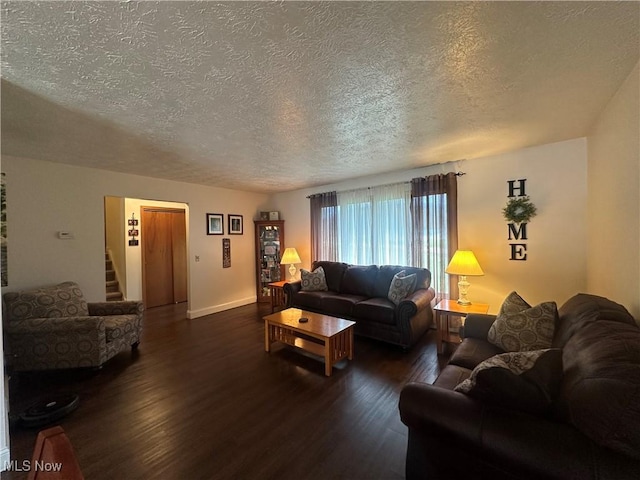 living area with dark wood-type flooring, a textured ceiling, and baseboards