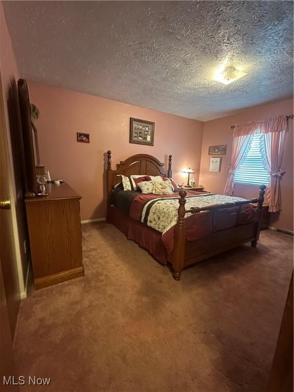 bedroom with a textured ceiling and light carpet