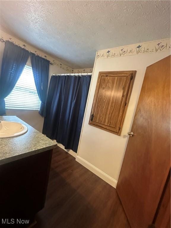 bathroom featuring vanity, baseboards, a textured ceiling, and wood finished floors