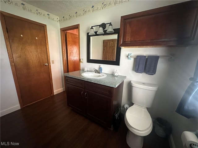 bathroom with baseboards, vanity, toilet, and wood finished floors