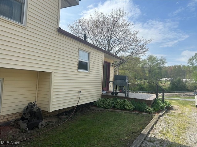view of side of property featuring a lawn and a deck