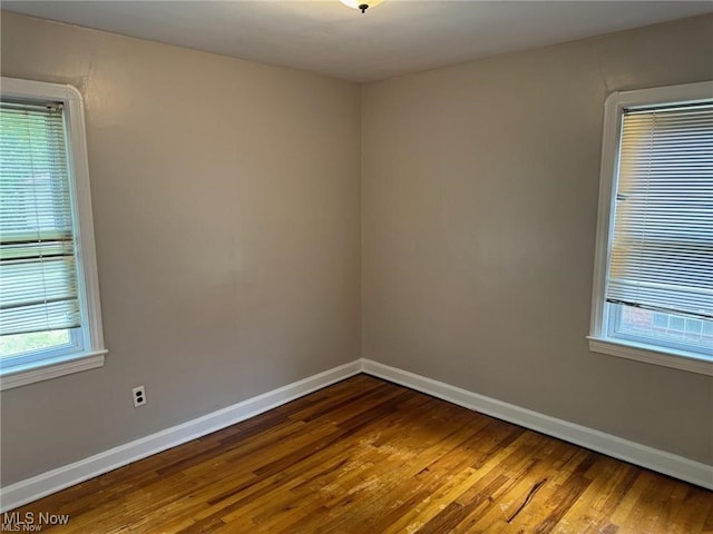 spare room featuring baseboards and wood finished floors