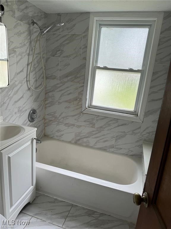 bathroom featuring  shower combination, marble finish floor, and vanity