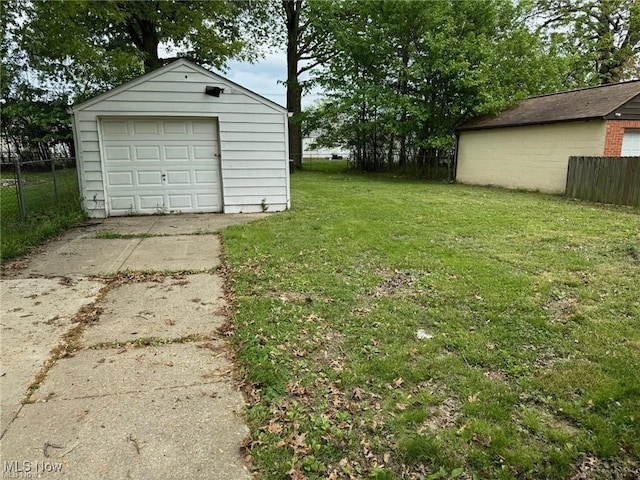 view of yard featuring an outdoor structure, fence, driveway, and a detached garage
