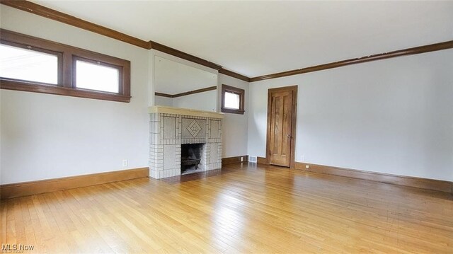 3996 Bluestone Rd, Cleveland Heights, OH 44121 - unfurnished living room featuring crown molding, baseboards, a brick fireplace, and light wood finished floors