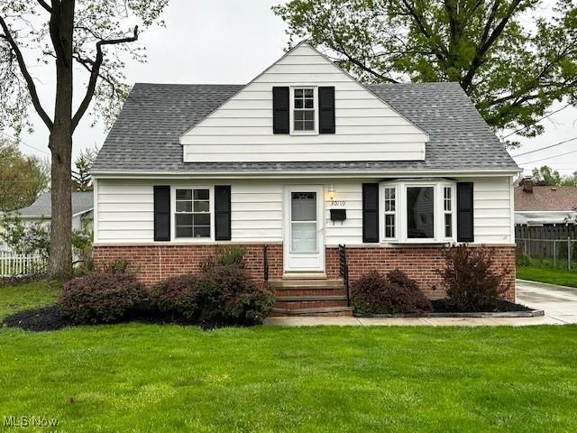 30119 Harrison St, Willowick, OH 44095 - view of front of house with brick siding, a shingled roof, a front lawn, and fence