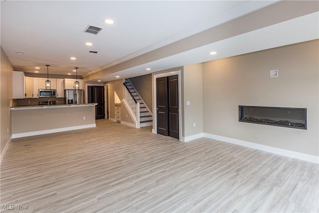 unfurnished living room with light wood-style floors, stairs, recessed lighting, baseboards, and visible vents