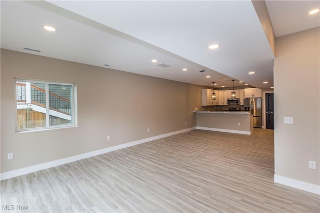 unfurnished living room with recessed lighting, baseboards, visible vents, and light wood-style floors