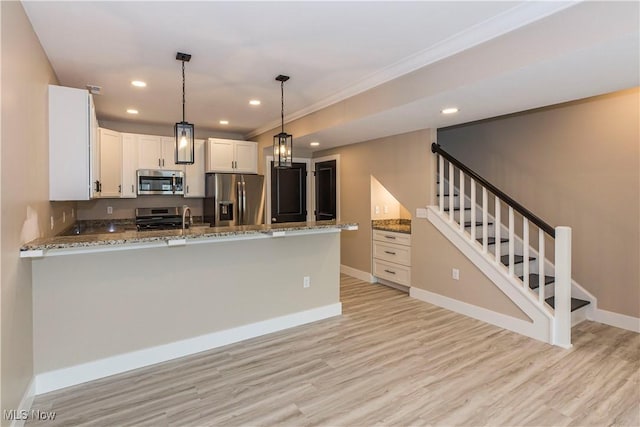 kitchen with light wood-style floors, appliances with stainless steel finishes, light stone countertops, and a peninsula