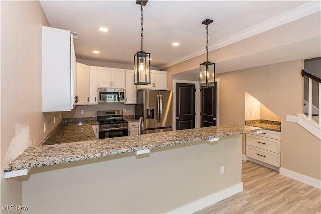 kitchen with white cabinets, light stone countertops, appliances with stainless steel finishes, a peninsula, and ornamental molding