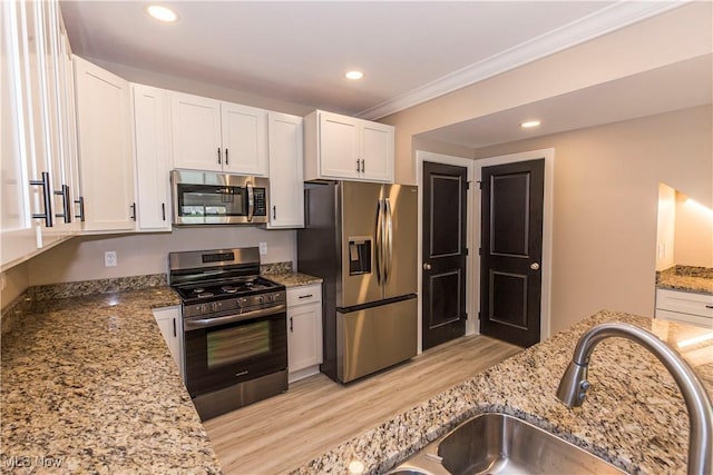 kitchen with a sink, light stone counters, light wood-style floors, ornamental molding, and stainless steel appliances