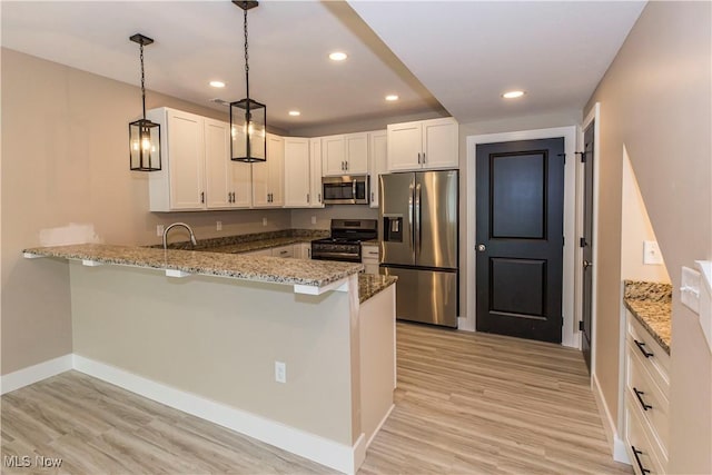 kitchen with appliances with stainless steel finishes, light stone countertops, baseboards, a peninsula, and light wood-style floors