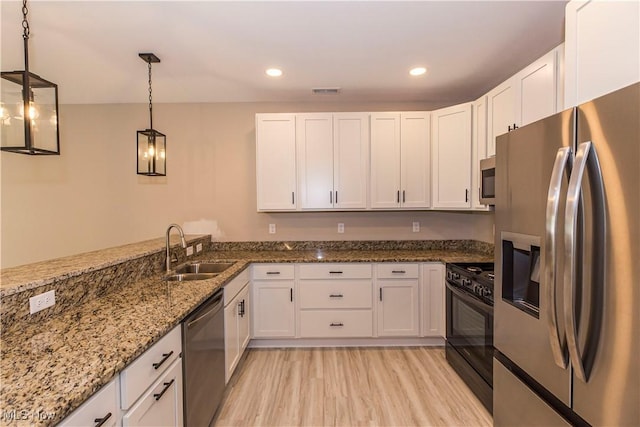 kitchen featuring stainless steel appliances, white cabinetry, a sink, and light wood-style floors